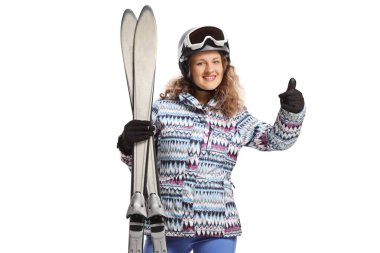 Beyaz arka planda izole edilmiş baş parmak hareketi gösteren bir çift kayağı olan genç kadın.