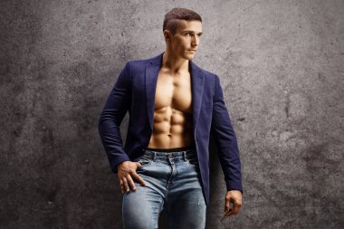 Gri bir duvara yaslanan yakışıklı erkek model. 