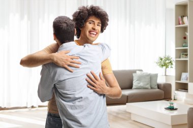 İki genç adam bir dairede birbirlerine sarılıyorlar.