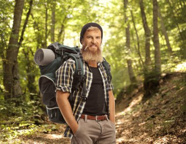 Ormanda duran sırt çantalı genç sakallı bir yürüyüşçü.