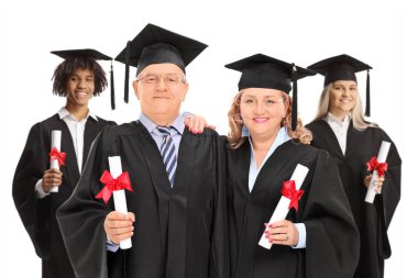 Olgun erkek, kadın ve mezuniyet elbiseli genç öğrenciler beyaz arka planda izole edilmiş.