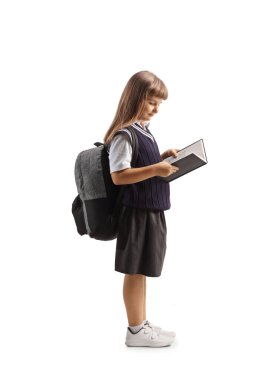 Okul üniformalı bir çocuk beyaz arka planda izole edilmiş bir kitap okuyor.