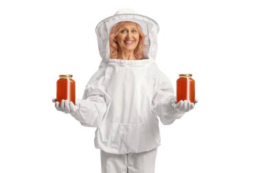 Woman bee keeper holding jars of honey and smiling isolated on white background clipart