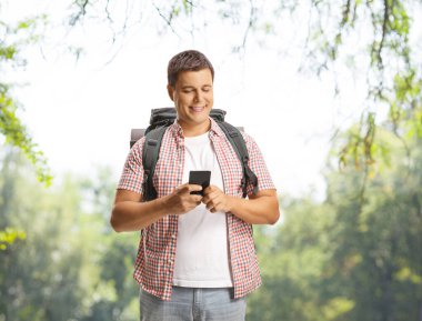 Sırt çantalı bir adam dışarıda akıllı telefon kullanıyor.