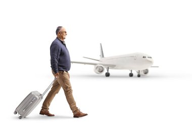 Beyaz arka planda izole edilmiş bir uçağa doğru yürüyen ve bavulu çeken olgun bir adam.