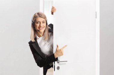 Kapıda duran ve işaret eden kulaklıklı kadın çağrı operatörü.