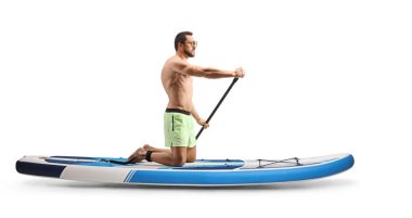 Full length profile shot of a man paddling a SUP board on knees isolated on white background