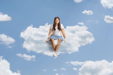 Genç kız gökyüzünde bir bulutta oturuyor.