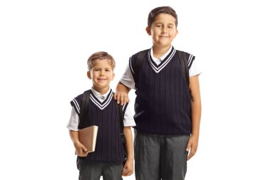 Üniformalı iki okul çocuğu beyaz arka planda yalnız poz veriyor.