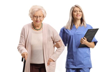 Mavi üniformalı hemşire beyaz arka planda izole edilmiş yaşlı bir kadın hastaya eşlik ediyor.