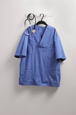 Bir sağlık görevlisi üniforması ve duvarda asılı steteskop. 