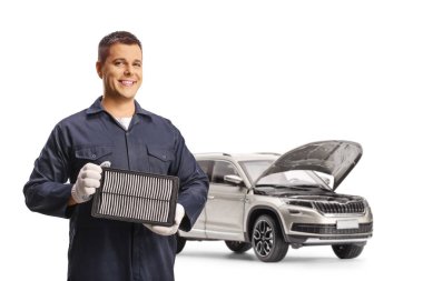 Otomatik tamirci beyaz arkaplanda izole edilmiş bir cipin önünde hava filtresi tutuyor