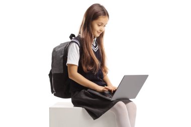 Dizüstü bilgisayarı olan liseli kız beyaz arka planda izole halde oturuyor ve daktilo yazıyor.