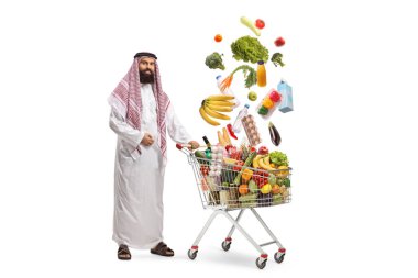 Arap adam elinde gıda ürünleriyle dolu bir alışveriş arabasıyla beyaz arka planda izole edilmiş bir şekilde duruyor.