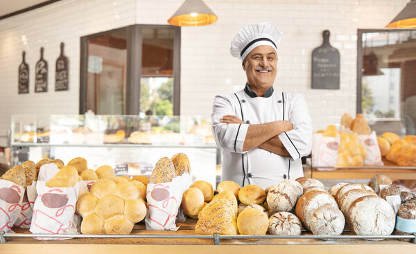 Cheerful mature male chef posing in a bakery