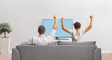 Baba oğul televizyon izleyip evde kutlama yapıyorlar.