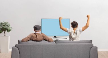 Büyükbabam ve torunum evde televizyon izleyip tezahürat yapıyorlar.