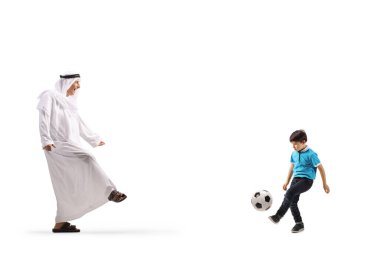 Beyaz bir grupta izole edilmiş bir çocukla futbol oynayan etnik kıyafetli bir Arap.