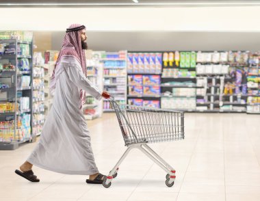 Suudi Arabistan 'lı bir adamın süpermarkette boş bir alışveriş yaparken tam boy profil fotoğrafı.