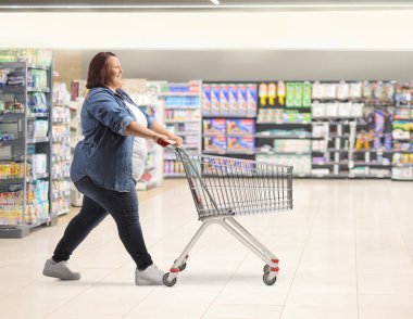 Markette boş bir alışveriş arabasını iten bir kadının tam boy profil fotoğrafı.