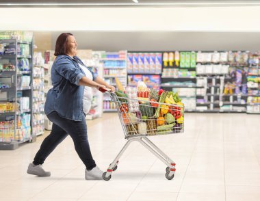 Aşırı kilolu birinin süpermarketten alışveriş yaparken tam boy profil fotoğrafı.