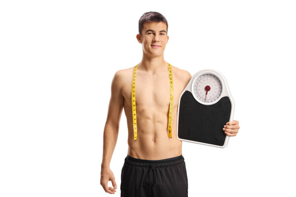 Male teenager with naked torso holding a weight scale and smiling isolated on white background