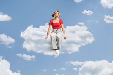 Filipinli genç bir kadın gökyüzünde bir bulutun üzerinde oturuyor. 