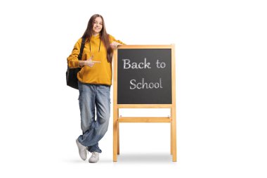 Genç öğrenci beyaz arka planda izole bir şekilde okula geri dönen bir tahtaya işaret ediyor.