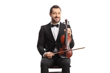 Genç ve zarif bir adam beyaz arka planda izole edilmiş bir kemanla oturuyor. 