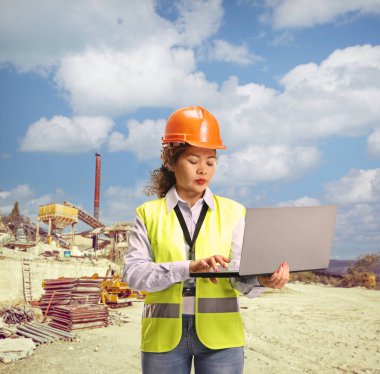 İnşaat alanında dizüstü bilgisayar kullanan Asyalı bir kadın mühendis.