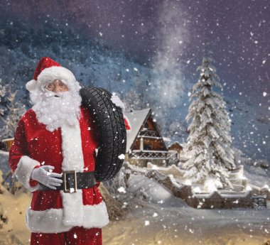 Noel Baba karlı bir dağda omzunda bir araba lastiği taşıyor.