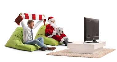 İş adamı, beyaz arka planda izole edilmiş Noel Baba 'yla televizyonda eşarp takıp futbol maçı seyrediyor.