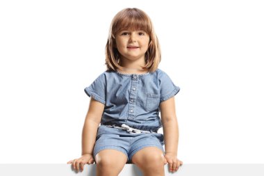 Panelde oturan ve beyaz arka planda izole edilmiş kameraya gülümseyen sevimli küçük kız.