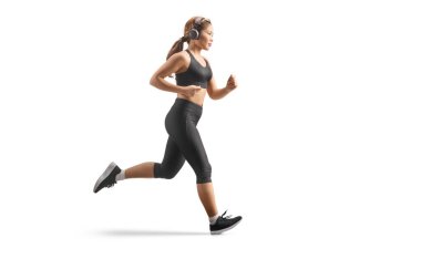 Beyaz arka planda izole edilmiş kulaklıklarla koşan Asyalı bir kadının tam boy profil fotoğrafı.