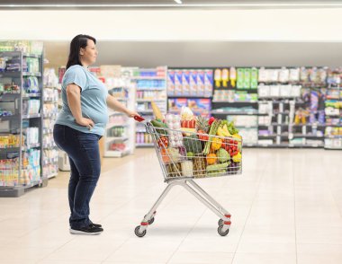 Markette boş alışveriş arabası olan bir kadının tam boy profil fotoğrafı.