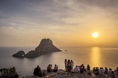 İbiza, İspanya - 26 Ağustos 2024 - Es Vedra adası manzarası ve gün batımını izleyen insanlar