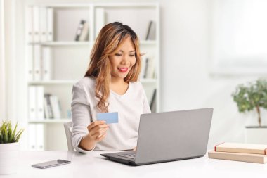 Asyalı kadın ev faturalarını dizüstü bilgisayar ve kredi kartıyla ödüyor.