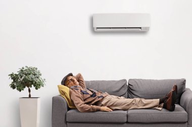 Yaşlı bir adam klimalı bir kanepede uyuyor. 