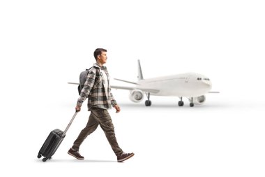 Bir öğrencinin bavul çekip beyaz arka planda izole edilmiş bir uçağa doğru yürüdüğü tam boy profil fotoğrafı.