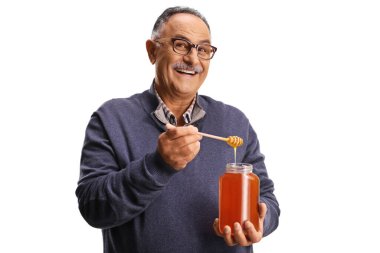Beyaz arka planda izole edilmiş kavanozdan bal almaya çalışan yaşlı bir adam.