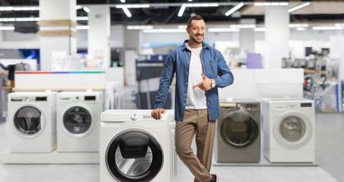 Delikanlı mağazadaki çamaşır makinesini işaret ediyor.