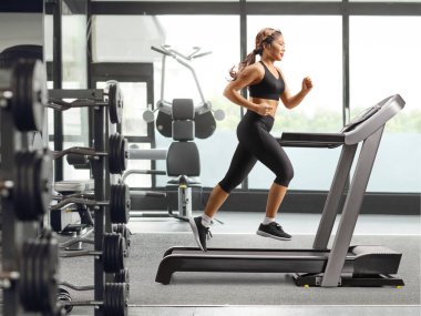 Genç Asyalı kadın spor salonunda koşu bandında koşuyor.