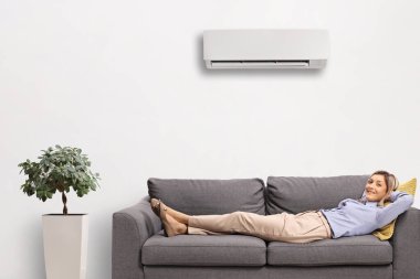 Klimalı bir odada kanepenin üzerinde dinlenen mutlu bir kadın.