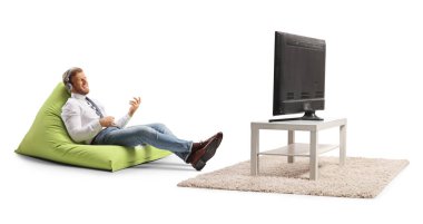 Fasulye çuvalında oturan ve beyaz arka planda izole bir şekilde televizyon karşısında müzik dinleyen bir iş adamı.