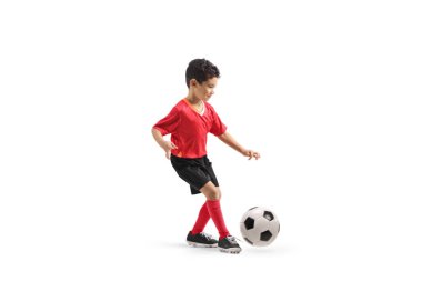 Kırmızı formalı, beyaz arka planda topu olan bir çocuğun tam boy profil çekimi.