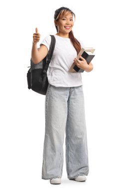 Asyalı kız öğrenci beyaz arka planda kitap tutuyor ve işaret ediyor.