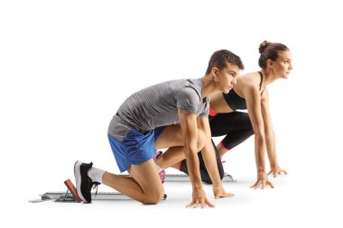 Beyaz arka planda izole edilmiş başlangıç bloklarında diz çöken erkek ve kadın koşucuların tam boy profil çekimi