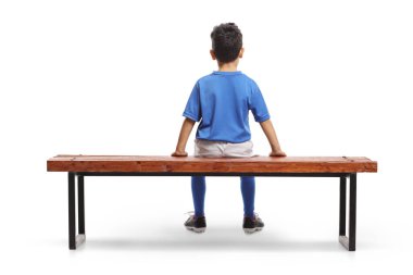 Beyazların arka planında izole bir şekilde futbol antrenmanında bankta oturan bir çocuğun arka plan çekimi.