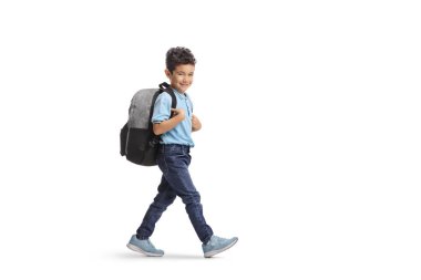 Sırt çantalı bir çocuk yürüyor ve beyaz arka planda izole edilmiş kameraya gülümsüyor.
