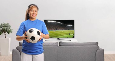 TV karşısında futbol maçı izleyen Asyalı bayan futbolcu.